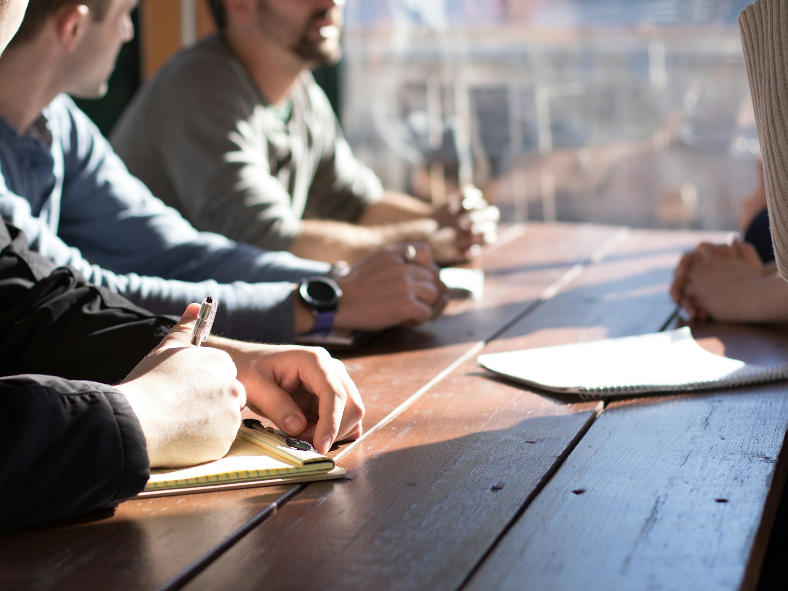 Small team of engineers planning a bot build at a wooden table